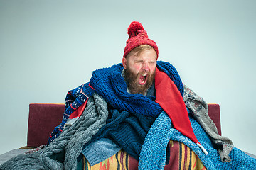 Image showing Bearded Man with Flue Sitting on Sofa at Home. Healthcare Concepts.