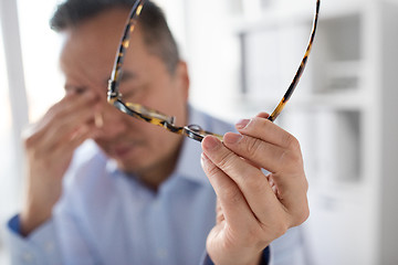 Image showing hand of tired businessman with glasses at office