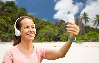 Image showing woman in phones takes selfie by cellphone on beach