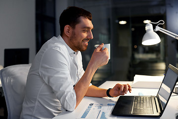 Image showing businessman with coffee and laptop at night office