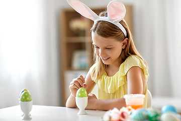 Image showing happy girl coloring easter egg at home