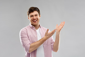 Image showing smiling young man showing something