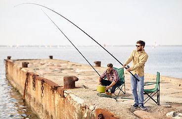 Image showing happy friends with fishing rods on pier