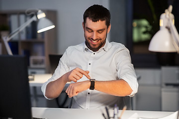 Image showing happy businessman with smart watch at nigh office