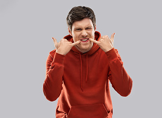 Image showing bully young man whistling over grey background