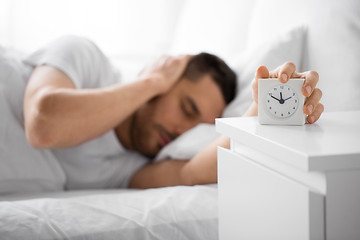 Image showing close up of man in bed reaching for alarm clock