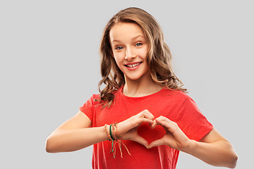 Image showing smiling teenage girl in red making hand heart