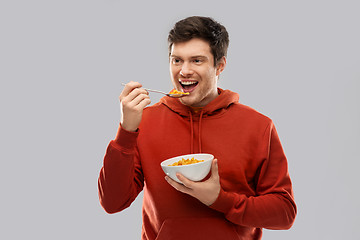 Image showing smiling young man in red hoodie eating cereals