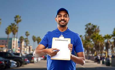 Image showing happy indian delivery man with clipboard in blue