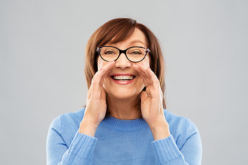 Image showing senior woman in glasses calling over grey