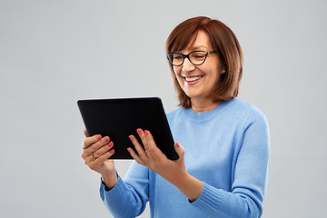 Image showing senior woman in glasses using tablet computer