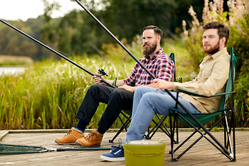 Image showing friends with fishing rods at lake or river