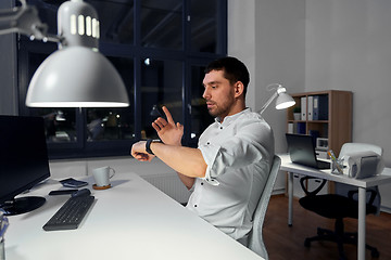 Image showing businessman using smart watch at nigh office