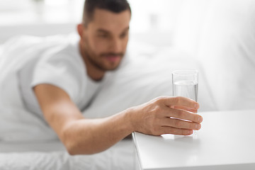 Image showing close up of man in bed reaching to glass of water