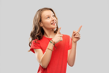 Image showing smiling teenage girl pointing fingers to something