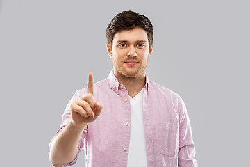 Image showing young man showing one finger over grey background