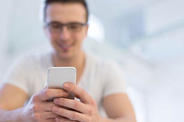 Image showing young man using a mobile phone  at home