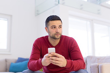 Image showing young man using a mobile phone  at home