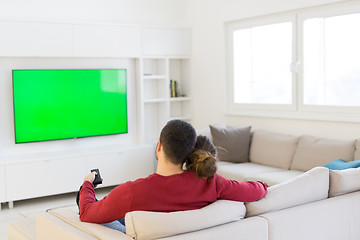 Image showing Young couple on the sofa watching television