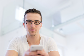 Image showing young man using a mobile phone  at home