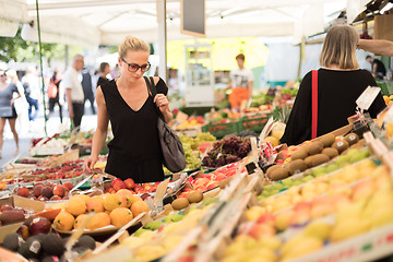 Image showing Woman buying fruits and vegetables at local food market. Market stall with variety of organic vegetable