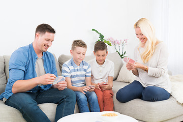 Image showing Happy young family playing card game at home.