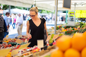 Image showing Woman buying fruits and vegetables at local food market. Market stall with variety of organic vegetable