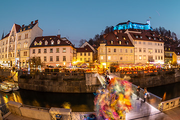 Image showing View of lively river Ljubljanica bank in old city center decorated with Christmas lights at dusk. Old medieval Ljubljana cstle on the hill obove the city. Ljubljana, Slovenia, Europe