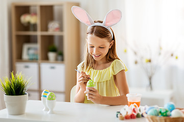 Image showing happy girl coloring easter eggs at home