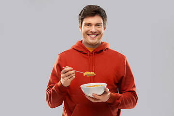 Image showing smiling young man in red hoodie eating cereals
