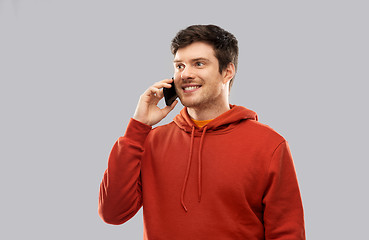 Image showing young man in red hoodie calling on smartphone