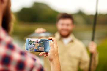 Image showing friend photographing fisherman by smartphone