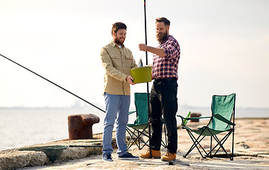 Image showing happy friends with fish and fishing rods on pier