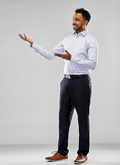 Image showing indian businessman holding something over grey