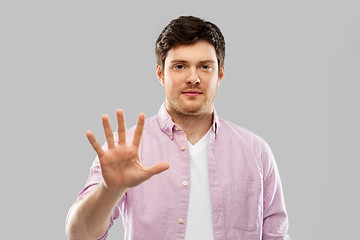 Image showing young man showing five fingers over grey