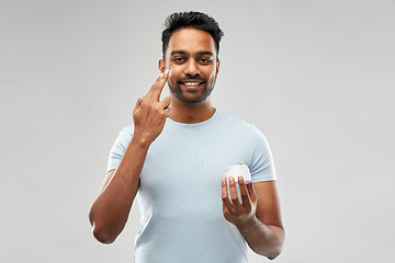 Image showing happy indian man applying cream to face