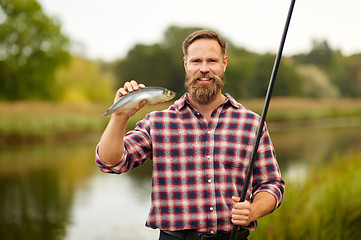 Image showing bearded fisherman with fishing rod and fish catch