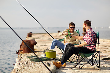 Image showing happy friends fishing and drinking beer on pier