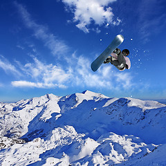 Image showing Skier Snowboarder jumping through air with sky in background