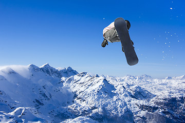 Image showing Skier Snowboarder jumping through air with sky in background