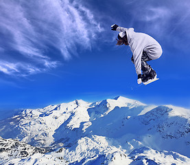 Image showing Skier Snowboarder jumping through air with sky in background