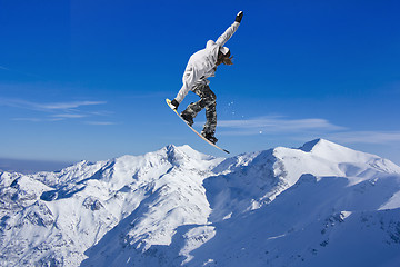 Image showing Skier Snowboarder jumping through air with sky in background