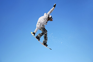 Image showing Snowboarder jumping through air with sky in background
