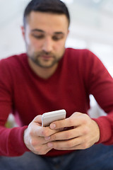 Image showing young man using a mobile phone  at home