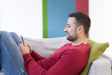 Image showing young man using a mobile phone  at home