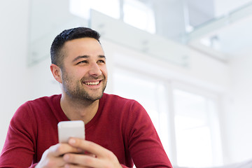 Image showing young man using a mobile phone  at home