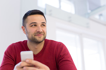 Image showing young man using a mobile phone  at home