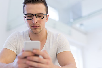 Image showing young man using a mobile phone  at home