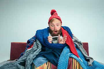 Image showing Bearded Man with Flue Sitting on Sofa at Home. Healthcare Concepts.