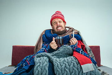 Image showing Bearded Man with Flue Sitting on Sofa at Home. Healthcare Concepts.